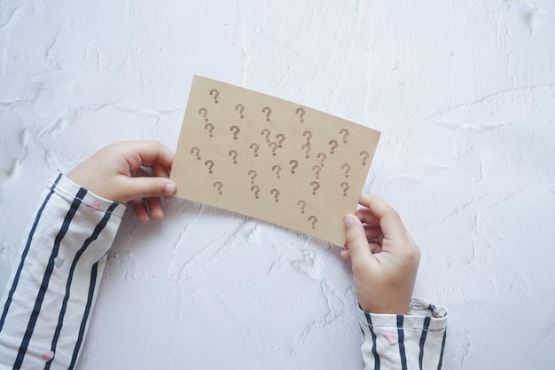 Child holding a question mark paper on white background