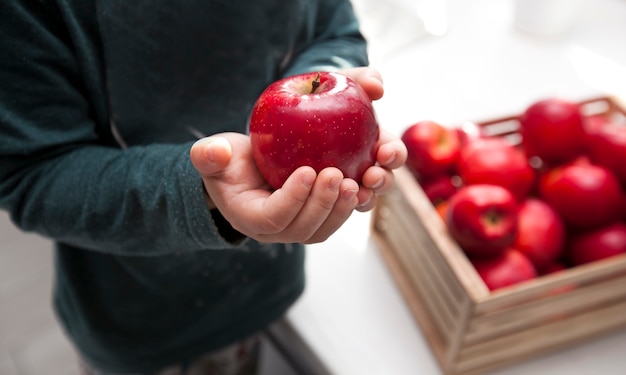 Child holding a red apple from a basket