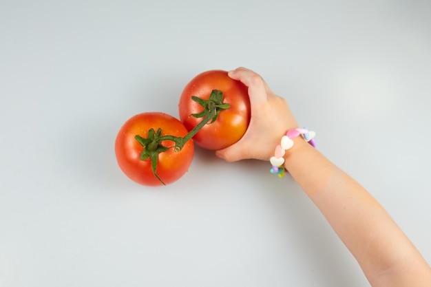 Child holding a tomato on a white background.