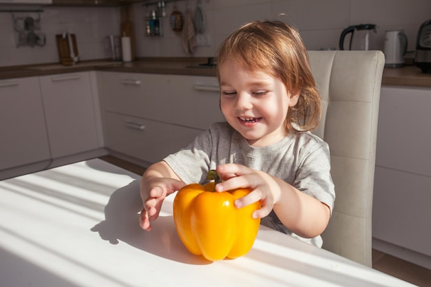 Child holding yellow paprika Healthy food concept Child nutrition Fresh vegetables in the hands of a cheerful boy child