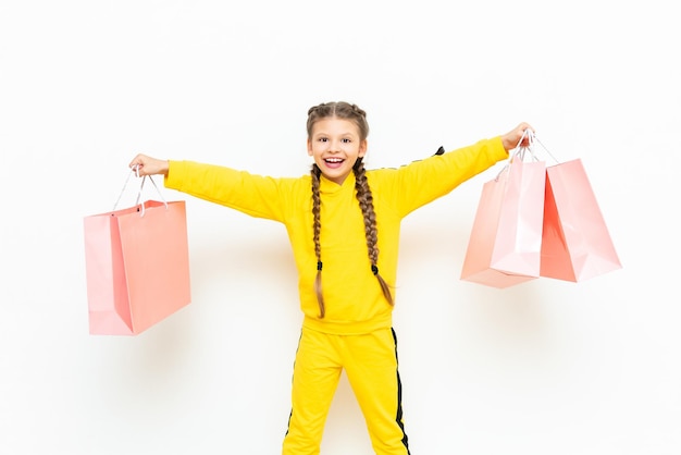 Il bambino tiene le borse con due mani bella bambina dopo lo shopping con sacchetti di carta