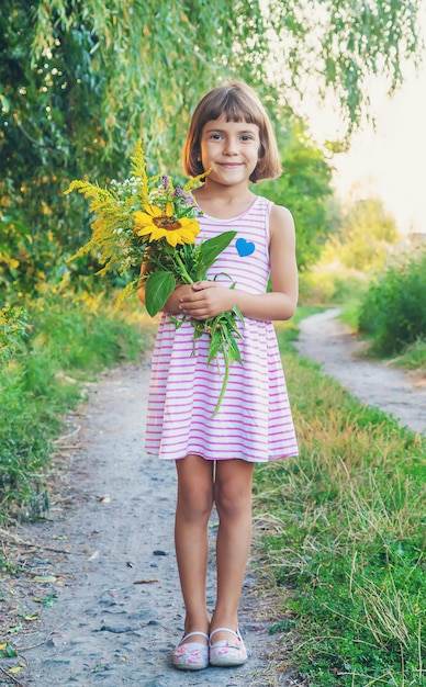 子供は彼の手で野生の花の花束を保持しています。