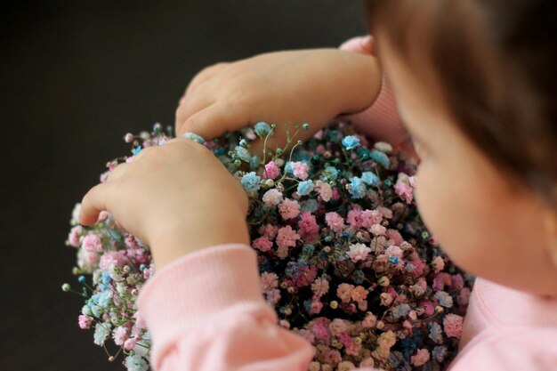 A child holds a bunch of flowers in a bowl.