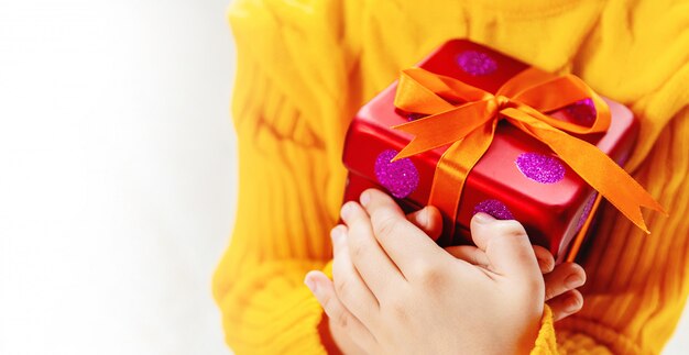 Child holds a Christmas decor and gifts on a white background. Selective focus.