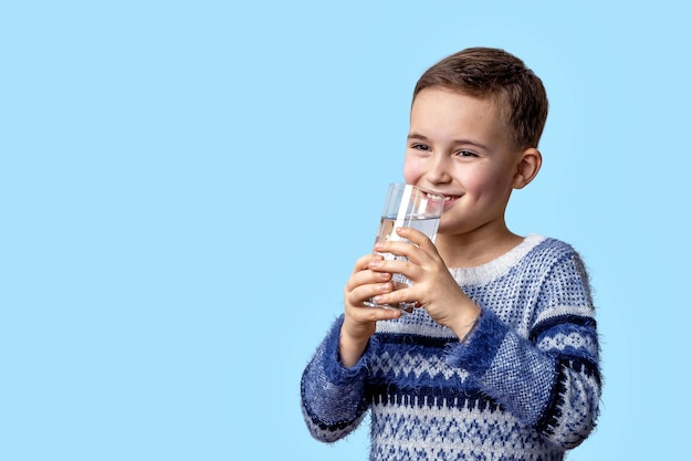 The child holds a glass of clean water in his hands and smiles