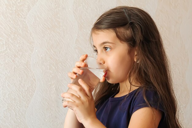 The child holds a glass of water in her hands. selective focus.people