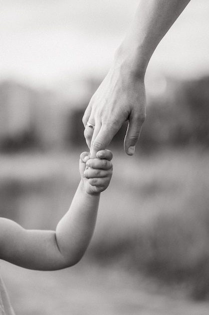 The child holds his mothers hand tightly black and white photo of the child with his mother closeup ...