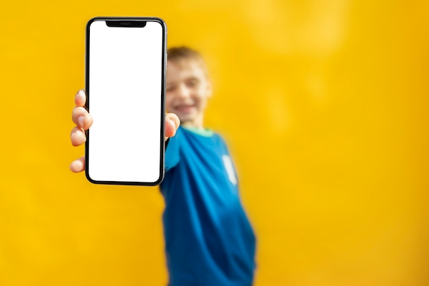 The child holds the phone in his hand for advertising on a yellow background. Color