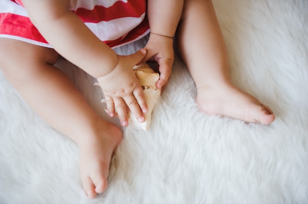 The child holds a seashell in his hands.