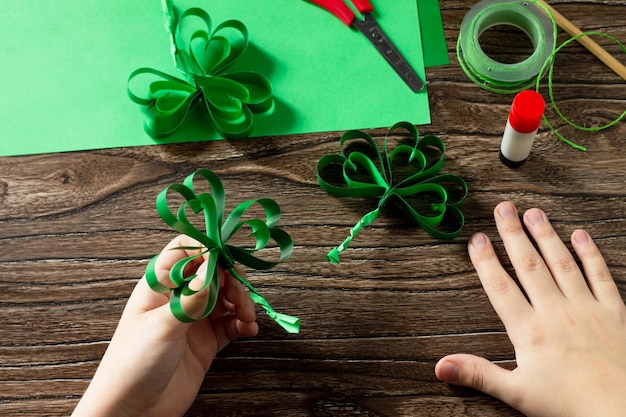 Child holds St Patricks Day clover craft from paper Handmade Childrens art project