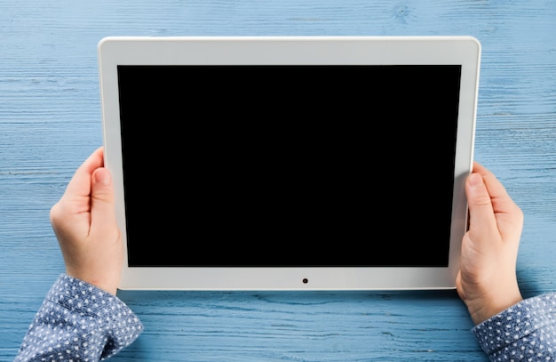 The child holds a tablet in his hands. Hands of a child with a tablet.