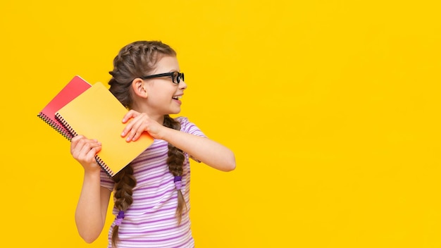 The child holds two notebooks in his hands and swings them with great joy