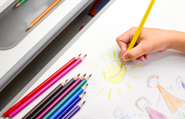 The child holds a yellow pencil in his hands and draws the sun Children's education concept