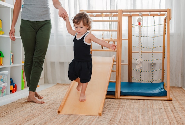 Child houdt zich bezig met het houten sportcomplex voor kinderen thuis.