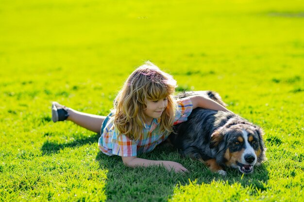 屋外で犬を抱きしめる子供は愛情を込めて彼のペットの犬を抱きしめる子供の男の子は子犬の犬とかわいい子供屋外の夏