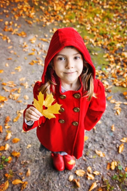 Фото Ребенок в красной шубе с осенними листьями. люблю осень. выборочный фокус.