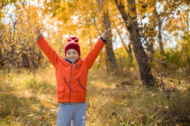 사진 가을 숲에서 낙엽 위를 걷고 있는 주황색 재킷을 입은 아이 자연 속에서 가을의 휴식