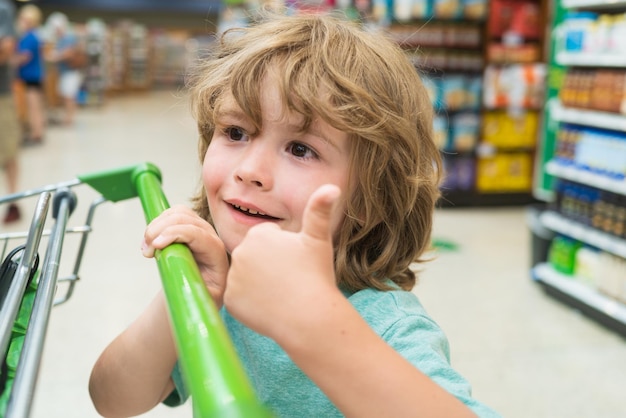 食料品のカートを持つスーパーマーケットの少年の子供