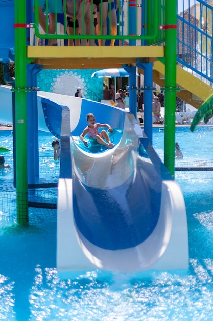 A child on an inflatable circle rides a water slide in a water park active summer vacation