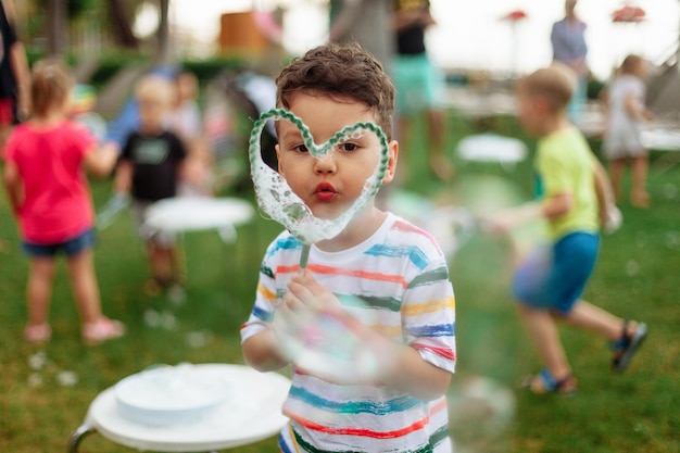 The child inflates large soap bubbles street animation program happy child on a green lawn summer va