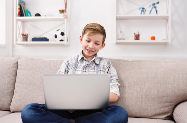 子供とインターネット、自宅でラップトップを持つ幸せな少年