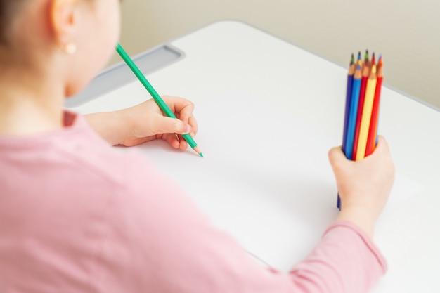 Child is drawing by colored pencil