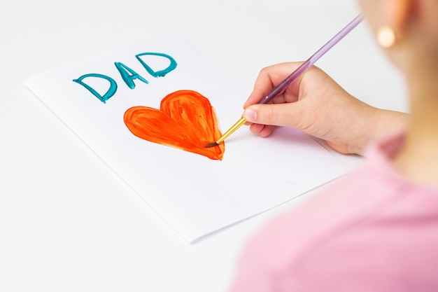 Child is drawing Father's day greeting card.