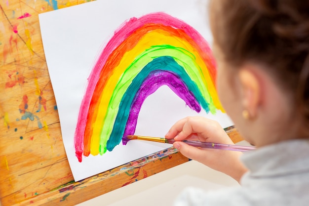 Ребенок рисует радугу на мольберте