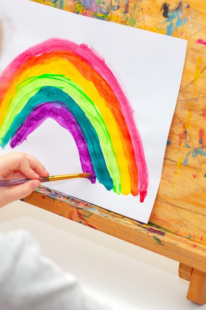 Il bambino sta disegnando l'arcobaleno.