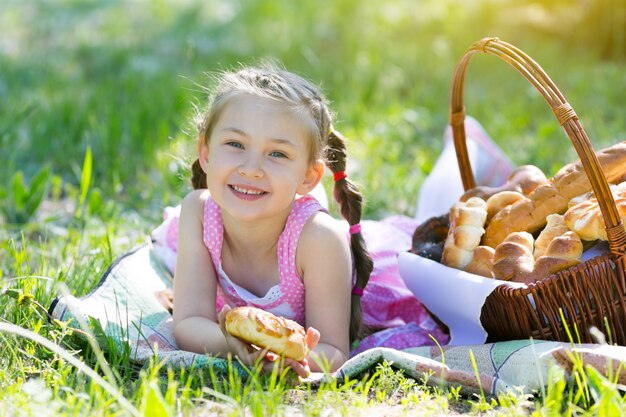 子供が草の上に座ってパンを食べています。