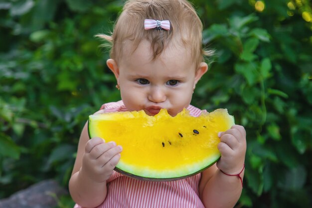 The child is eating a watermelon. Selective focus.