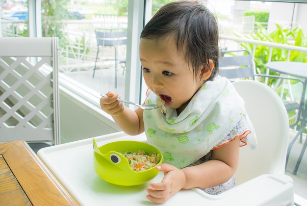 Foto un bambino sta mangiando da solo con il cucchiaio. bambino mangia.