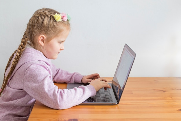 The child is engaged on a laptop. Concept of online lessons and home schooling