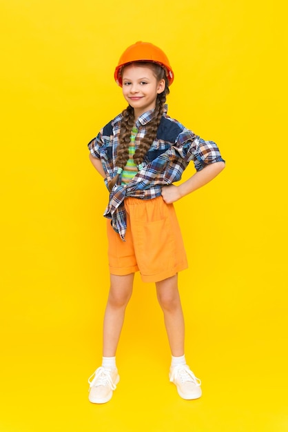 Photo the child is an engineer in a helmet and shirt a little girl is getting ready for renovation in the childrens room a teenager chooses the profession of an architect yellow isolated background