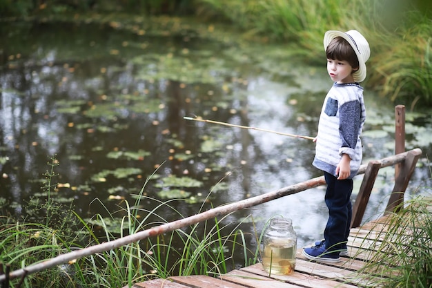 가을 아침에 한 아이가 낚시를 하고 있습니다. 연못에가 석양입니다. 산책로에 낚싯대를 든 어부.