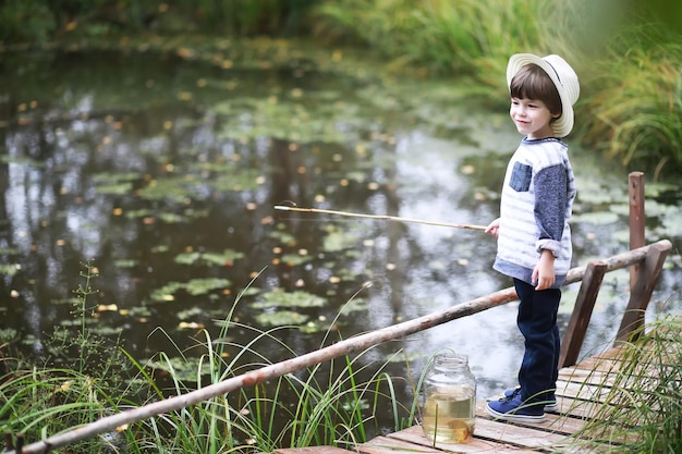 A child is fishing in the autumn morning Autumn sunset on the pond A fisherman with a fishing rod on the walkway