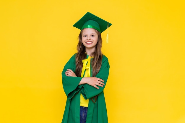 The child is a graduate A little girl in a graduate hat on a yellow isolated background Happy graduation to a little girl Graduation from elementary school