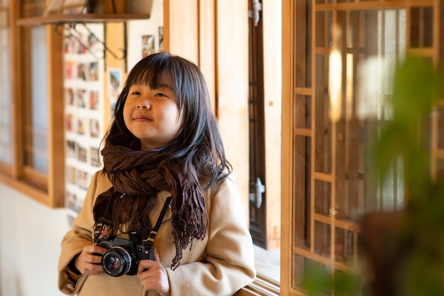 子供はカメラを持って、光が入る窓を見ています。