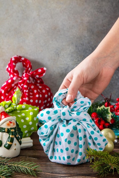 Il bambino sta tenendo i regali di natale nuovo anno e confezione regalo zero rifiuti furoshiki