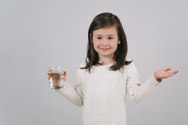 아이가 물 한 잔을 들고 있습니다. 소녀는 물을 마시고 싶어합니다.