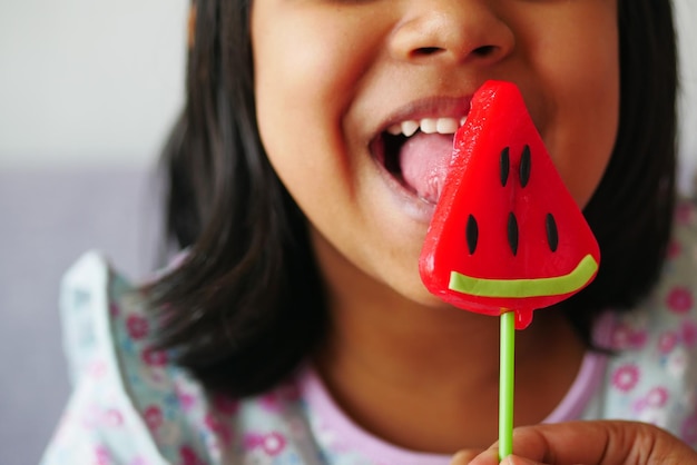 Ребенок лижет красочную конфету на палочке