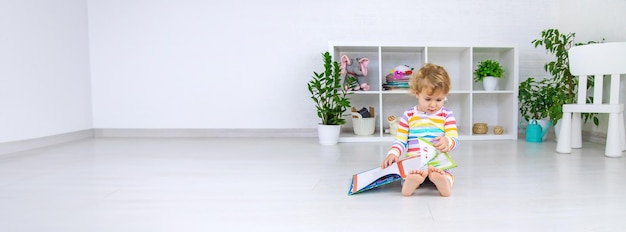 The child is looking at a book in the room Selective focus