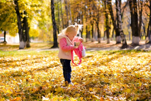 Child is looking for something in a backpack against the backdrop of an autumn landscape