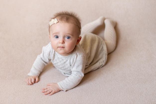 The child is lying on a beige background and smiling A happy contented child