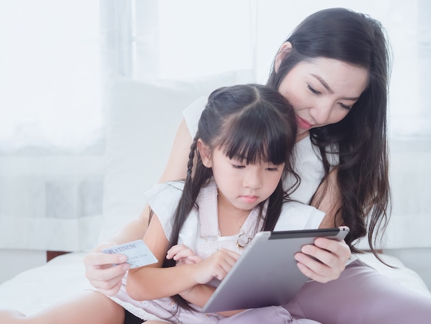 The child is playing in bed with her mother