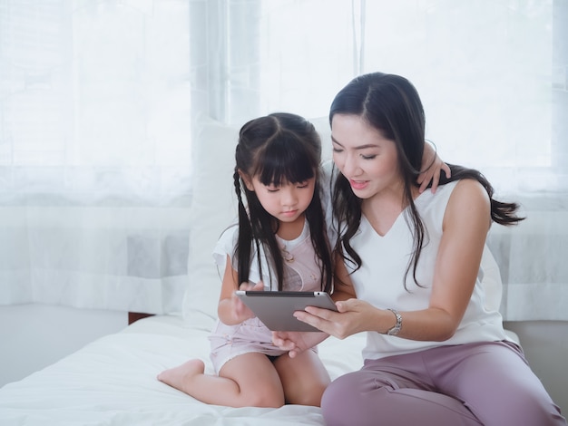 The child is playing in bed with her mother