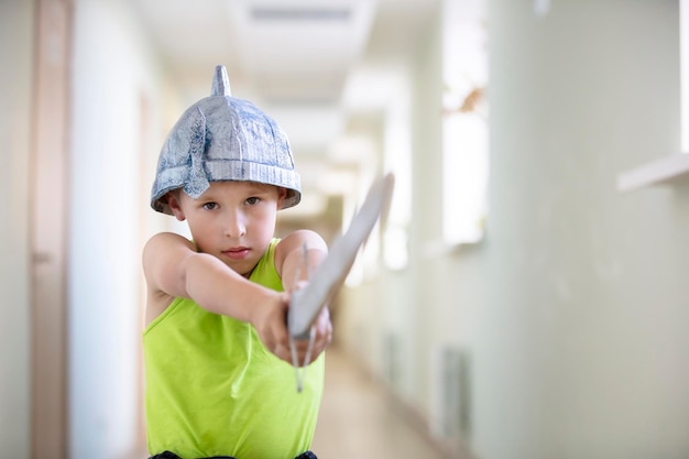 A child is playing warrior Funny boy in a helmet with a sword