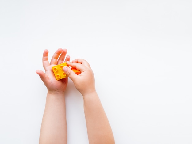 Child is playing with colorful constructor blocks. 