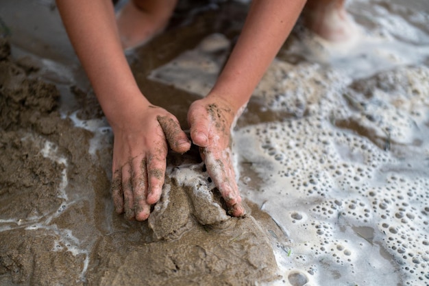 子供は手と水、遊びの詳細で、ビーチで砂で遊んでいます。