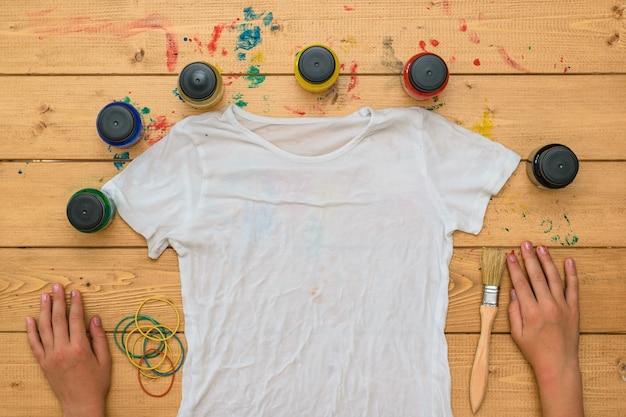 The child is preparing to apply paint on a t-shirt in the style of tie dye